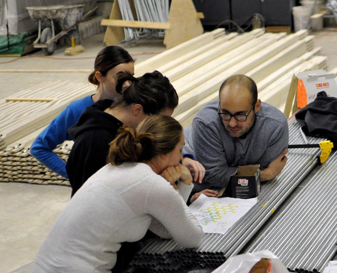 A group of students pour over a blueprint in a construction lab.