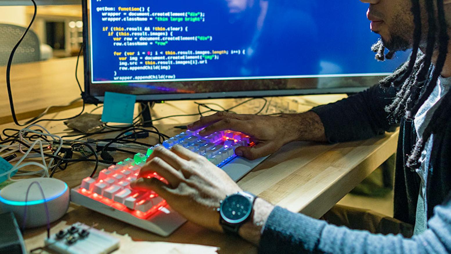 A close up a student using a keyboard with rainbow colored keys.