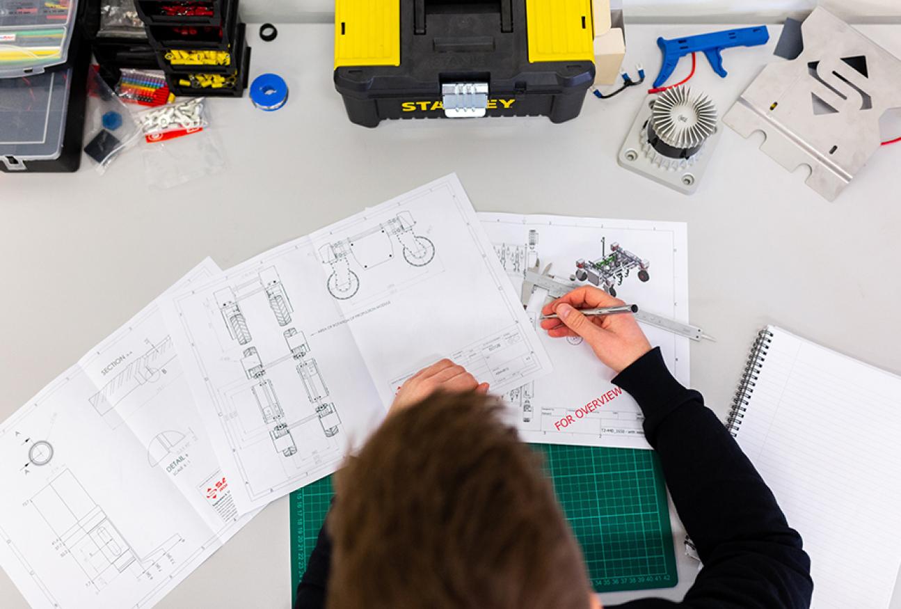 An overhead shoot of a person working on engineering sketches. 