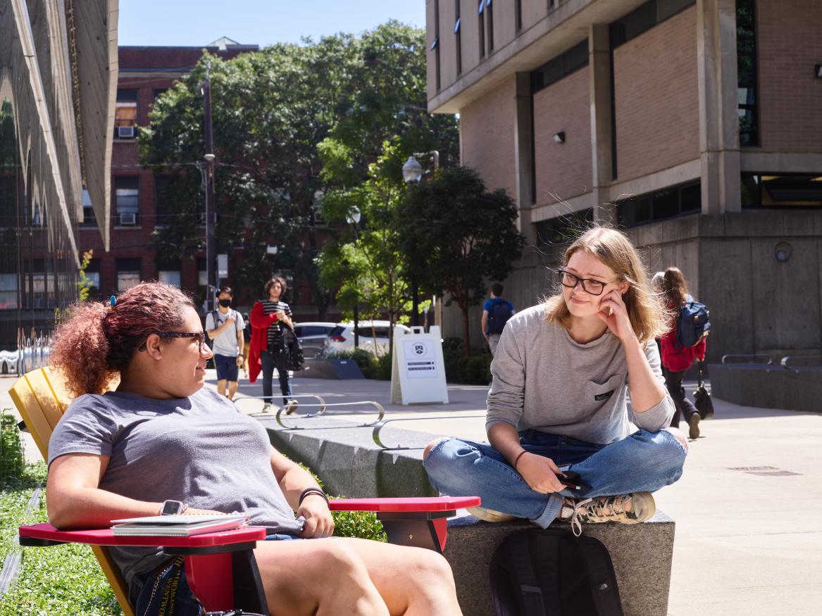 two students sitting by the building