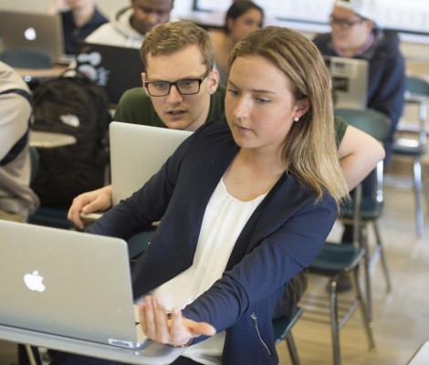 Two students discuss their project together in the classroom