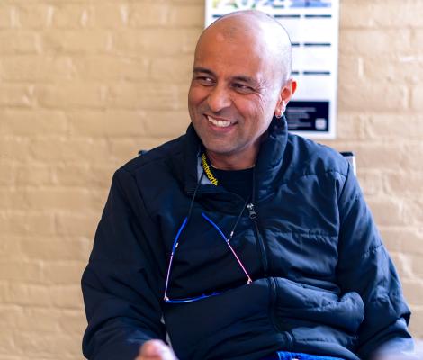 a man smiles while seated in a classroom