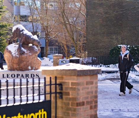 statue of a leopard in the snow with students walking by