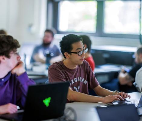 A classroom of students works with hands-on computing projects