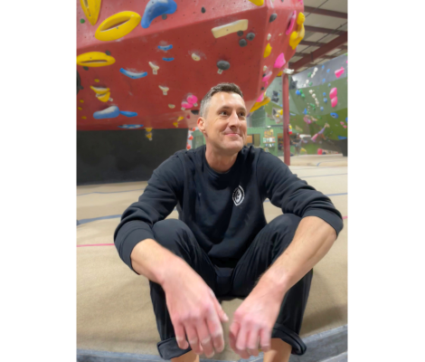a man sitting on the floor of a rock climbing gym