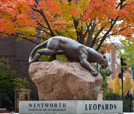 a statue of a leopard surrounded by autumn leaves