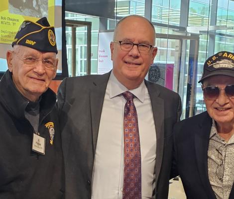 three men pose for a camera with two in military veteran dress