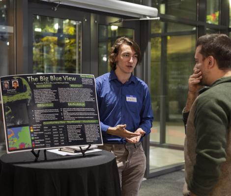 a student shows off an ai-related project to attendees of an event