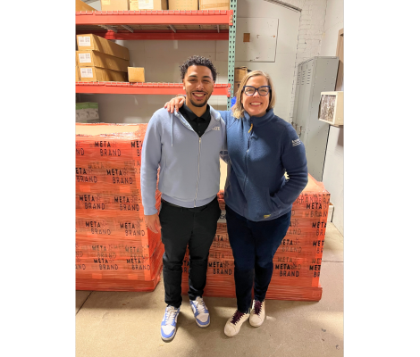 two people standing in front of pallets of beverages