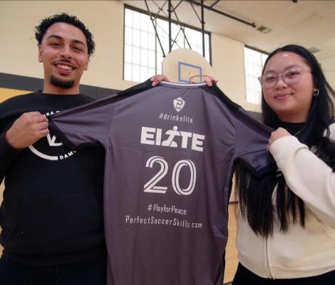 two people hold up an athletic shirt that reads "elite"