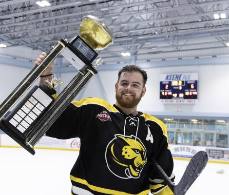 a man in a hockey uniform holds up a trophy