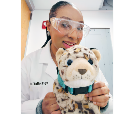 a woman in a lab coat holds a leopard stuffed animal