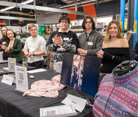 a group of students pose for a photo in front of clothing and other created materials