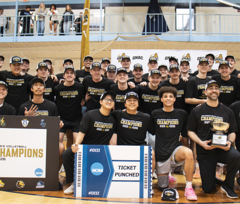 a team of volleyball players poses with a championship banner