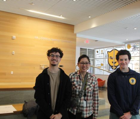 three people pose for the camera in an atrium area