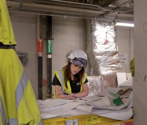 a woman in a hardhat looks over construction plans
