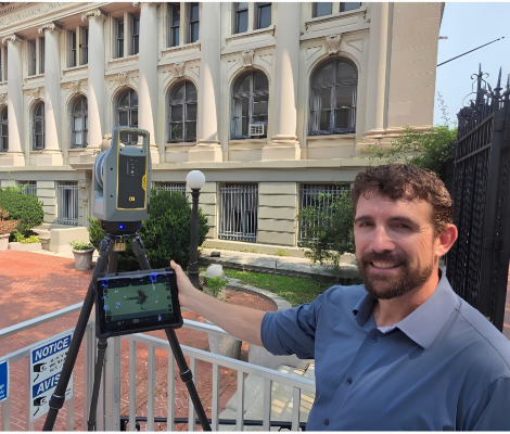 a man stands with a 3d scanner in front of a beaux-arts style building