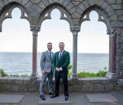 two men standing in front of large windows overlooking the water