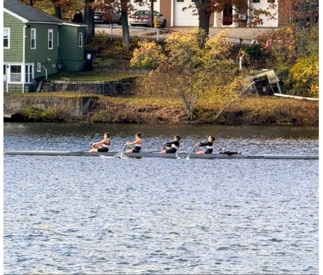four women in a boat rowing on the river