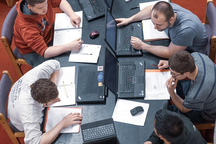 A group of 5 male students are captured studying from an overhead angle.