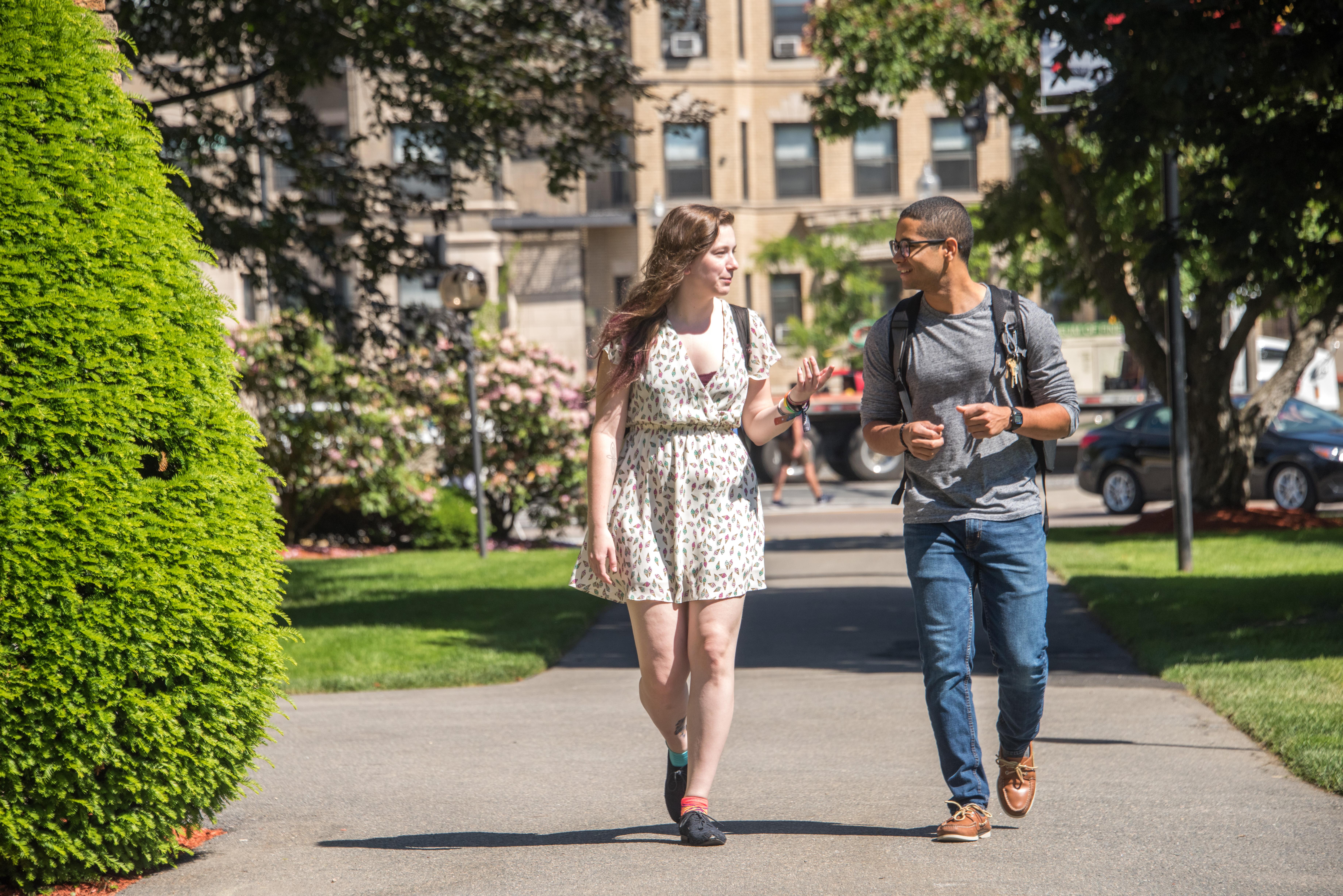 A man and woman walking and talking to each other.