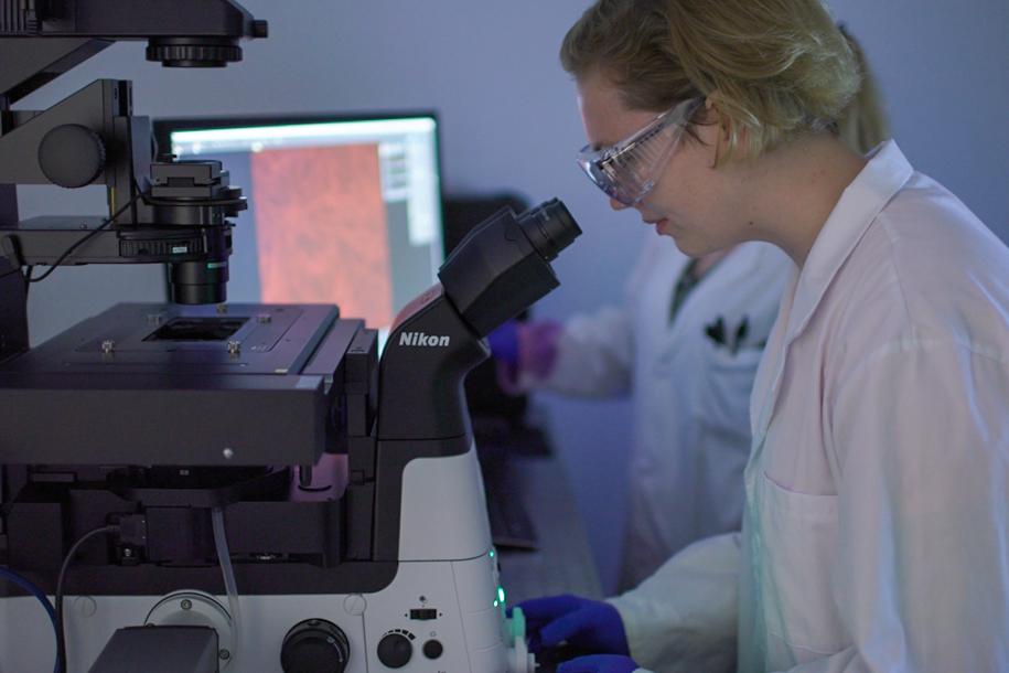 A woman looks into a microscope