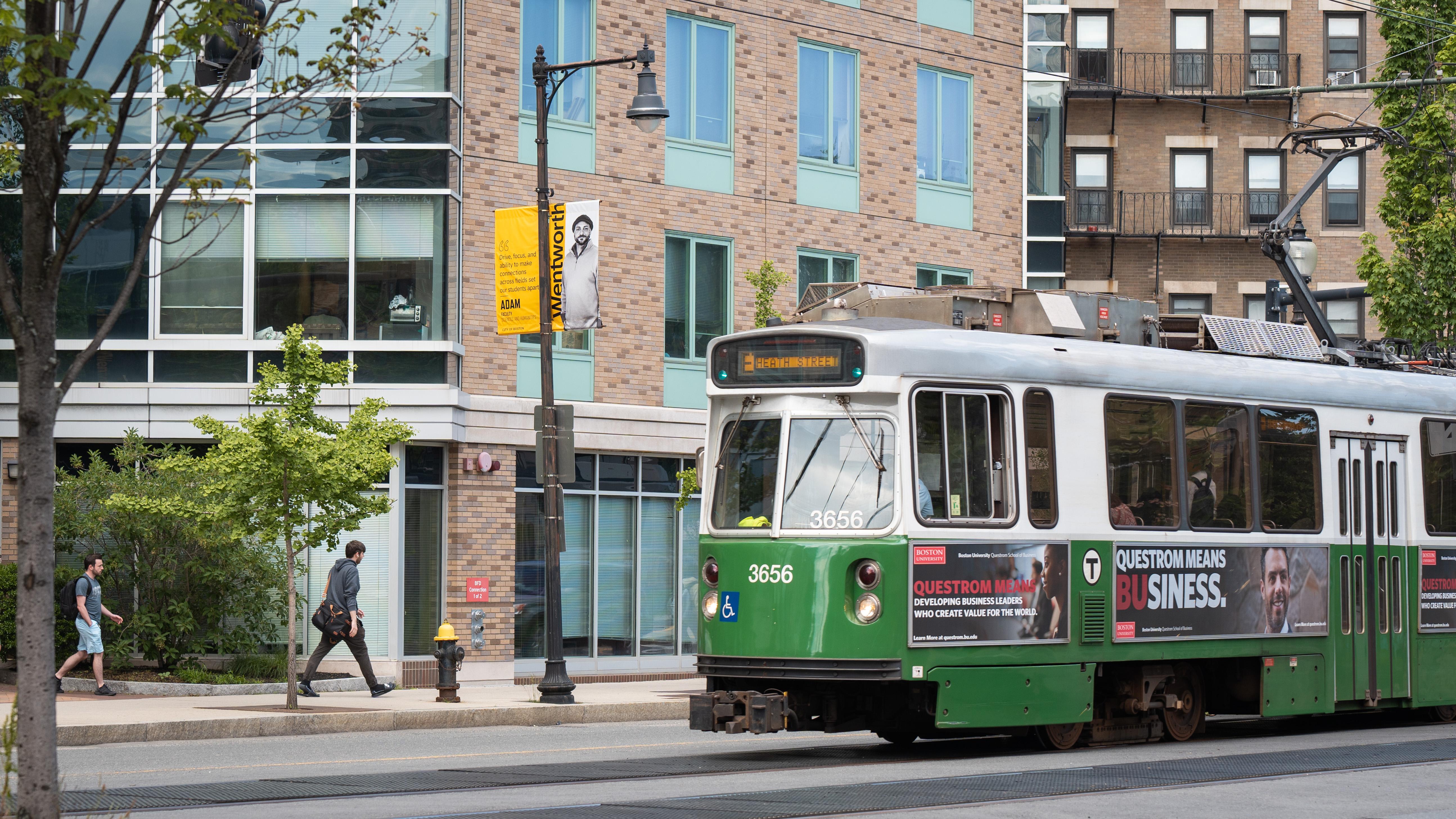 a green train moves past a building