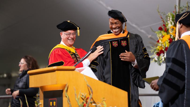 two men sharing a smile at a college commencement ceremony