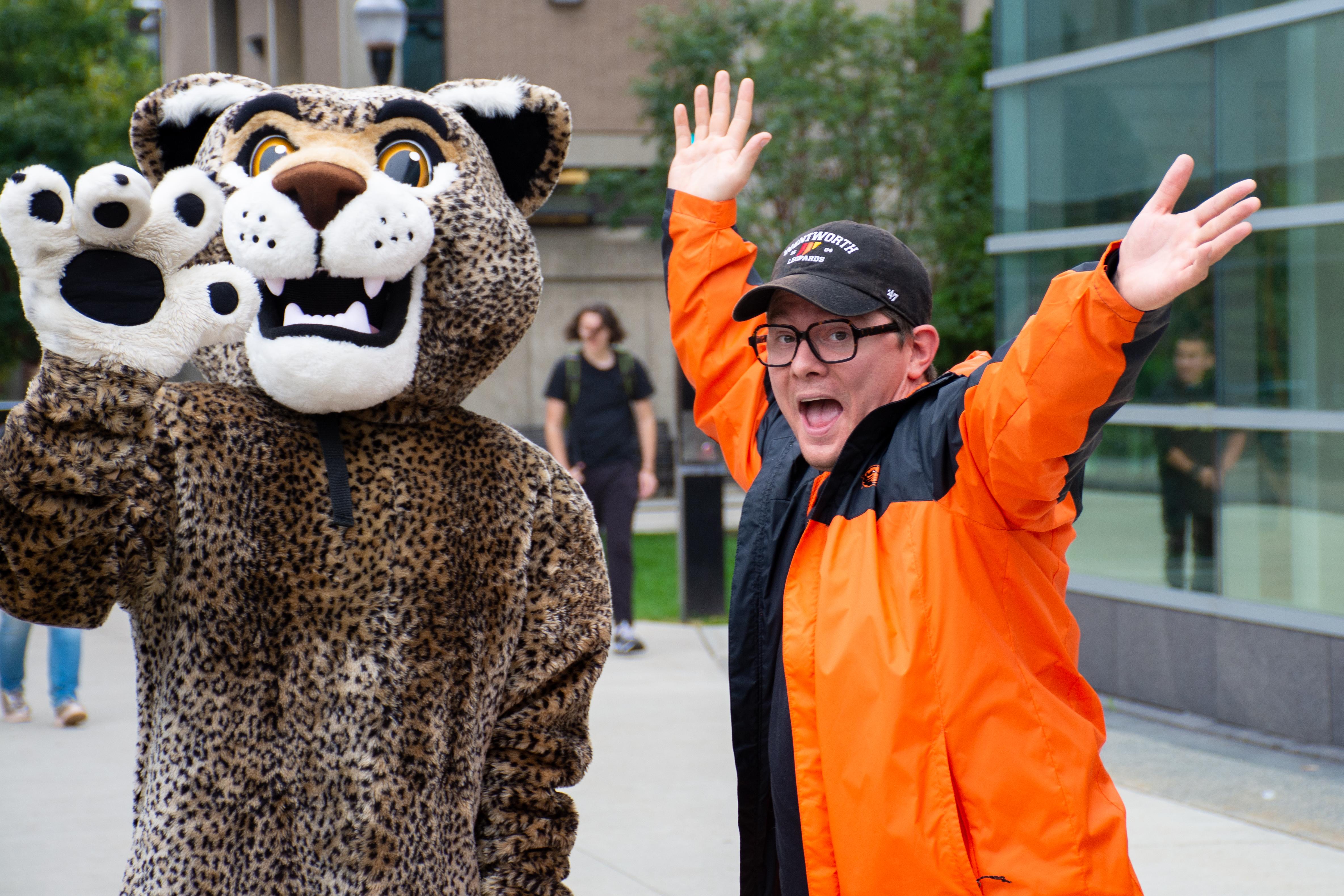 man posing with person in a leopard mascot costume