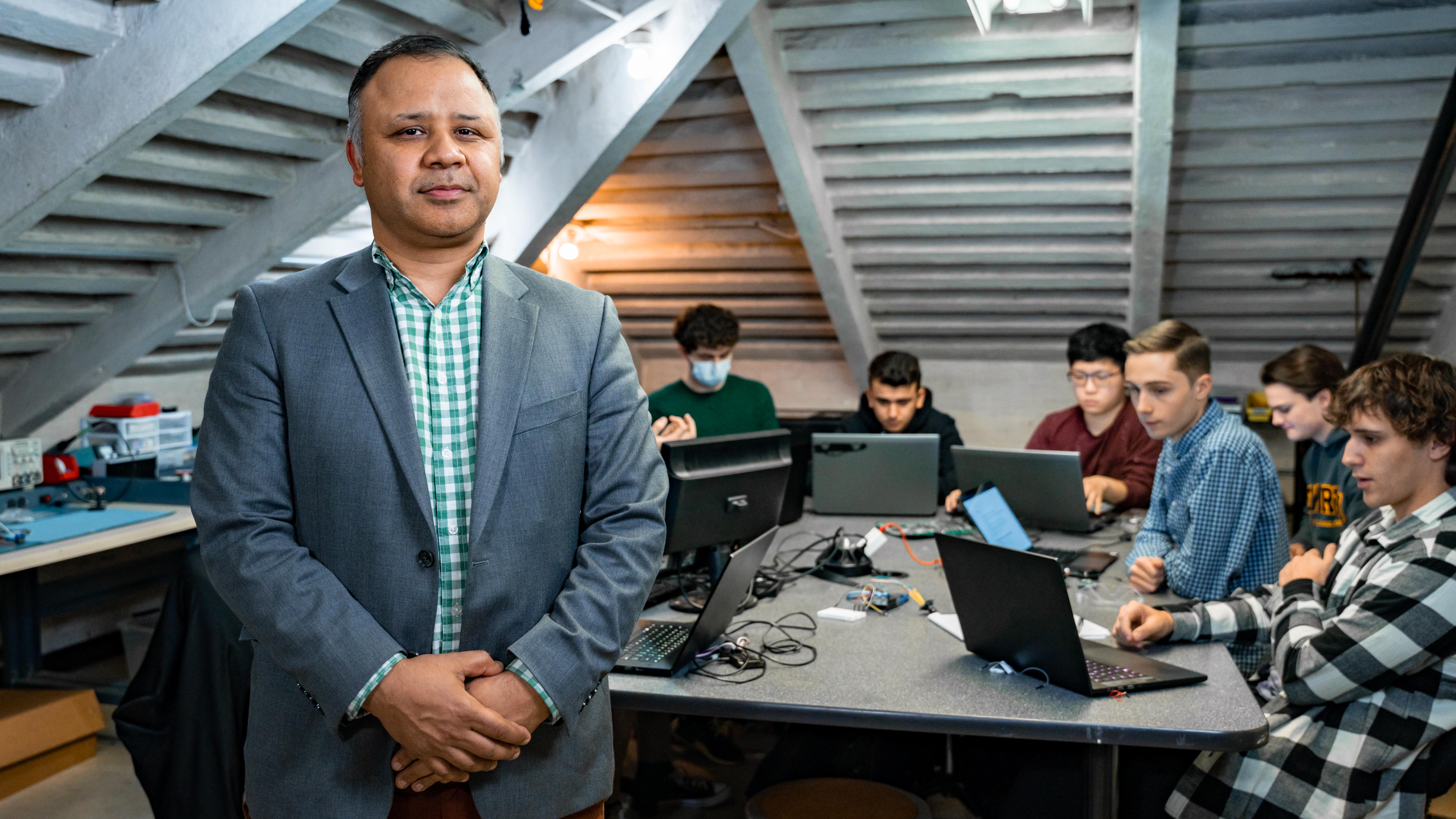 man in suit stands in front of group of students