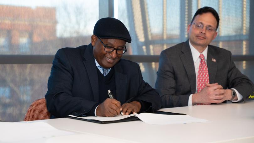 a man smiling as he signs a piece of paper