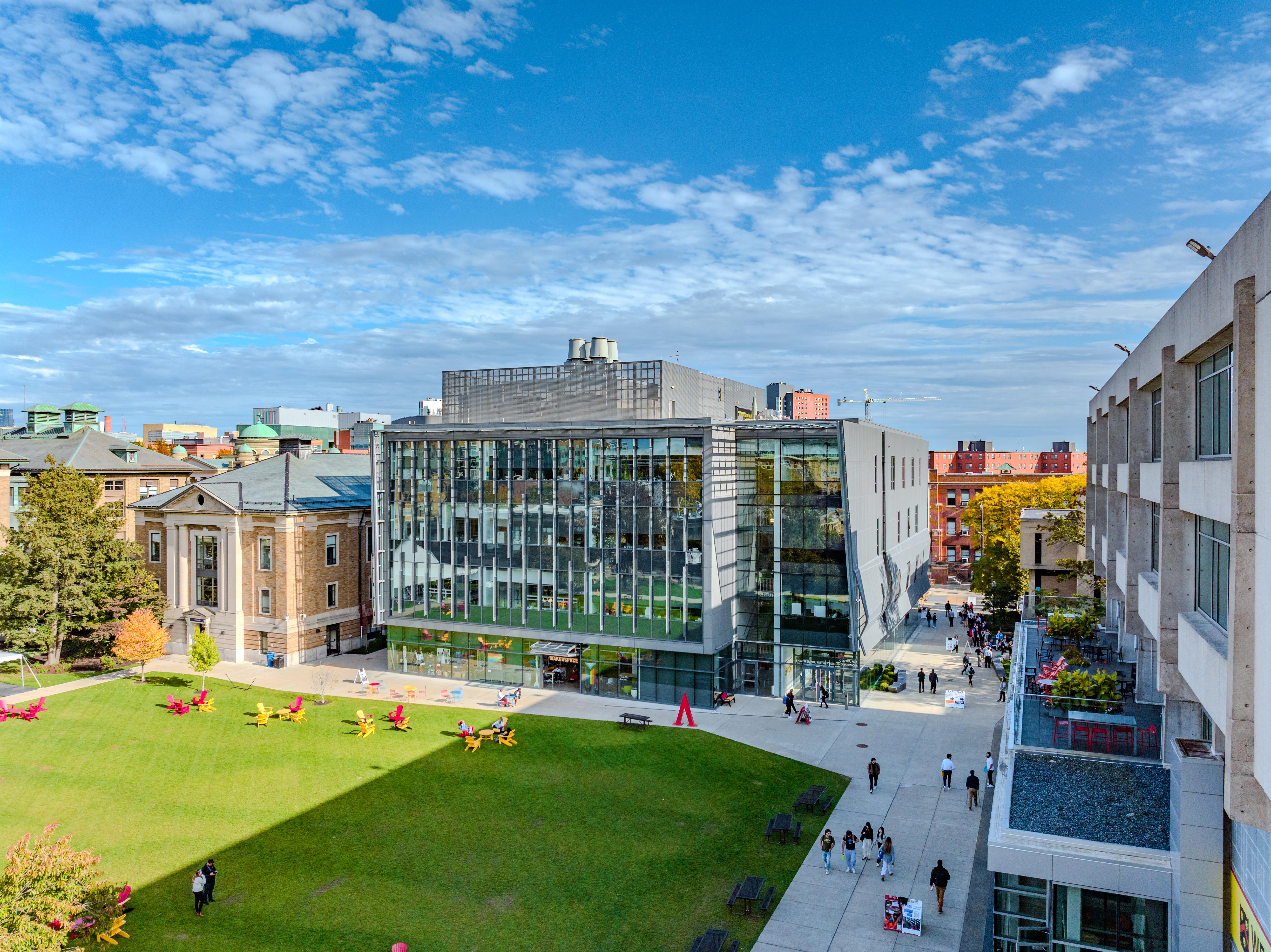 glass building with green space and city buildings surrounding it