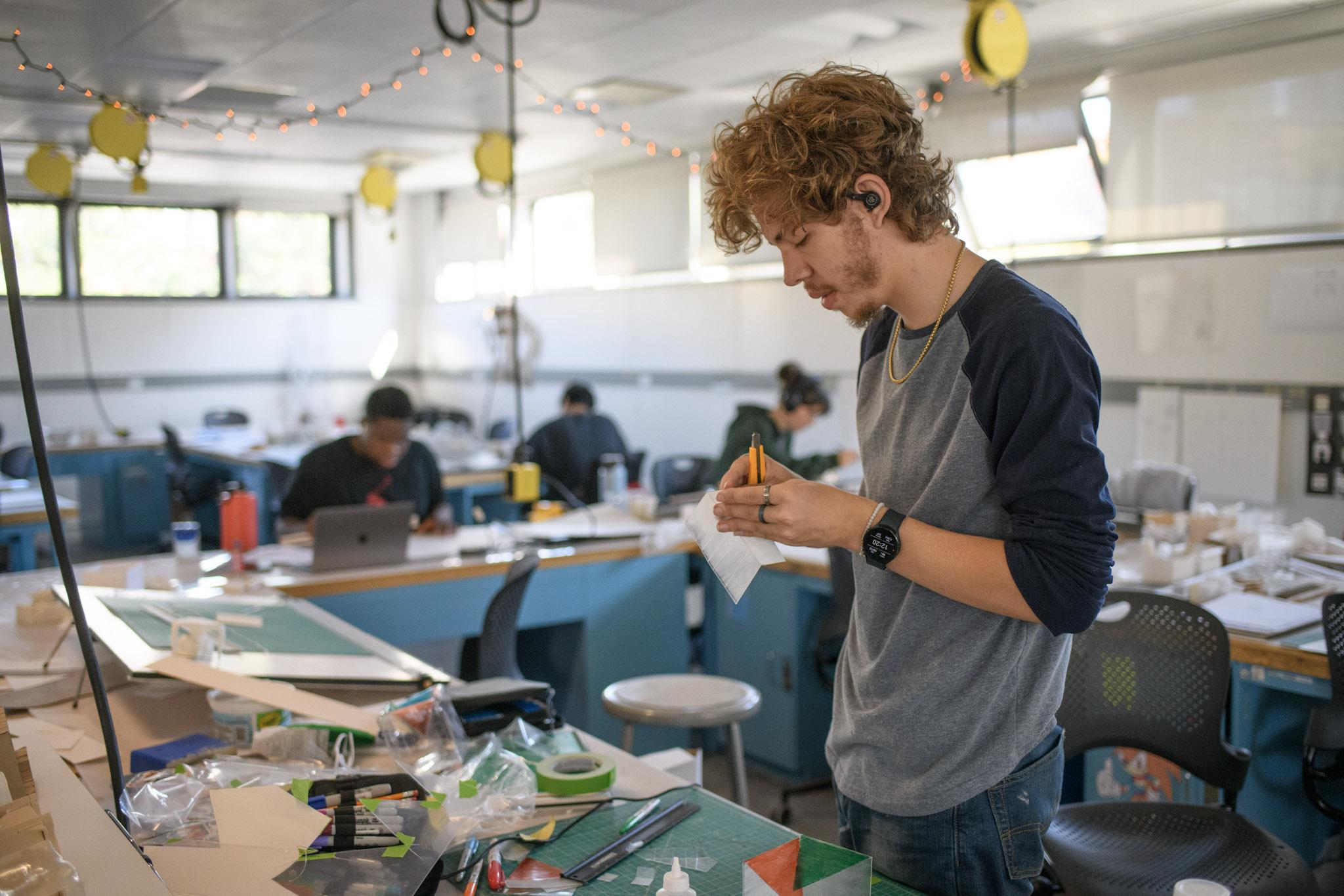 A Wentworth male student puts together project using an exacto knife in the architecture studio