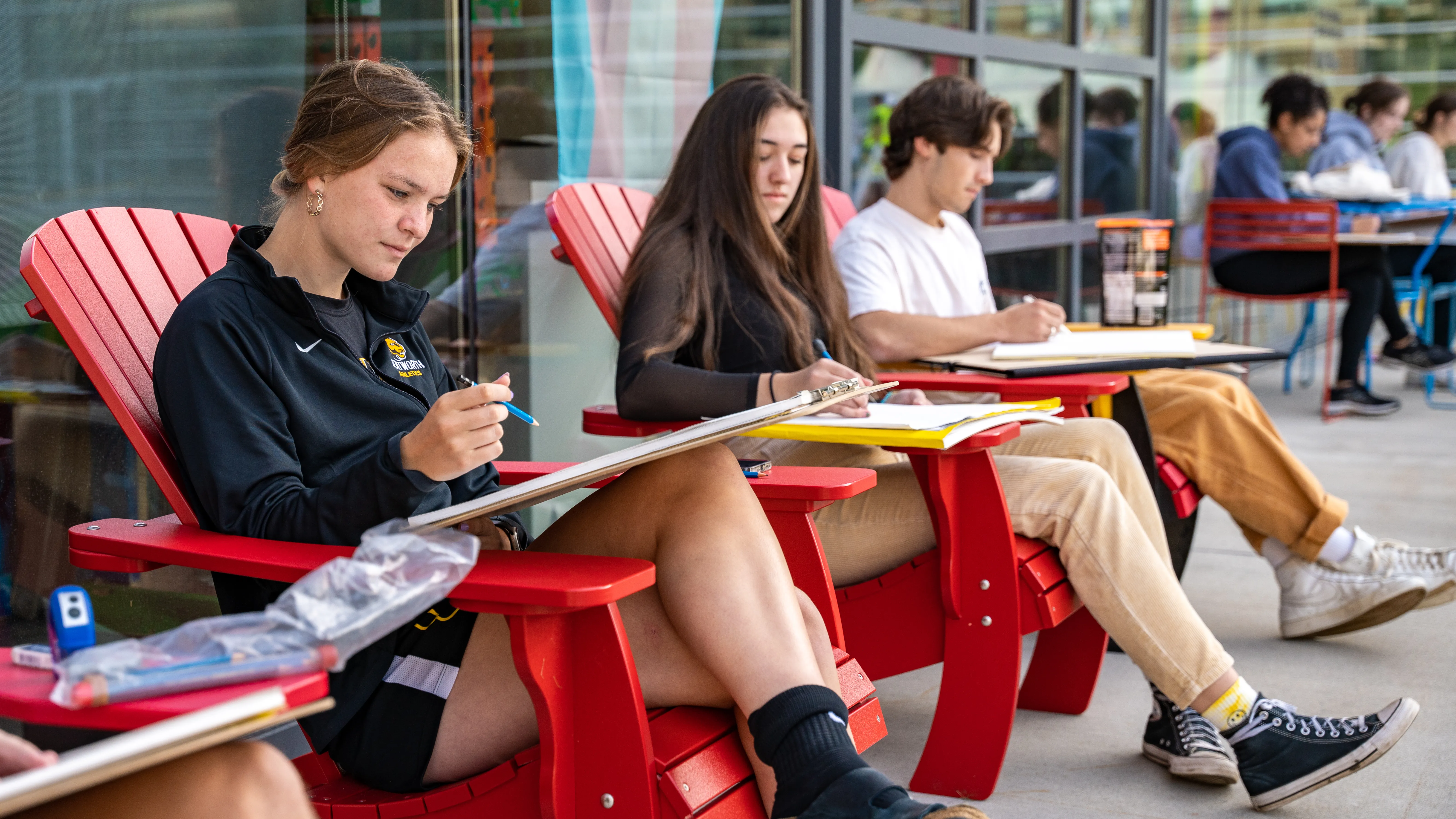 Students sitting in red Adirondack chairs outside of CEIS building. 