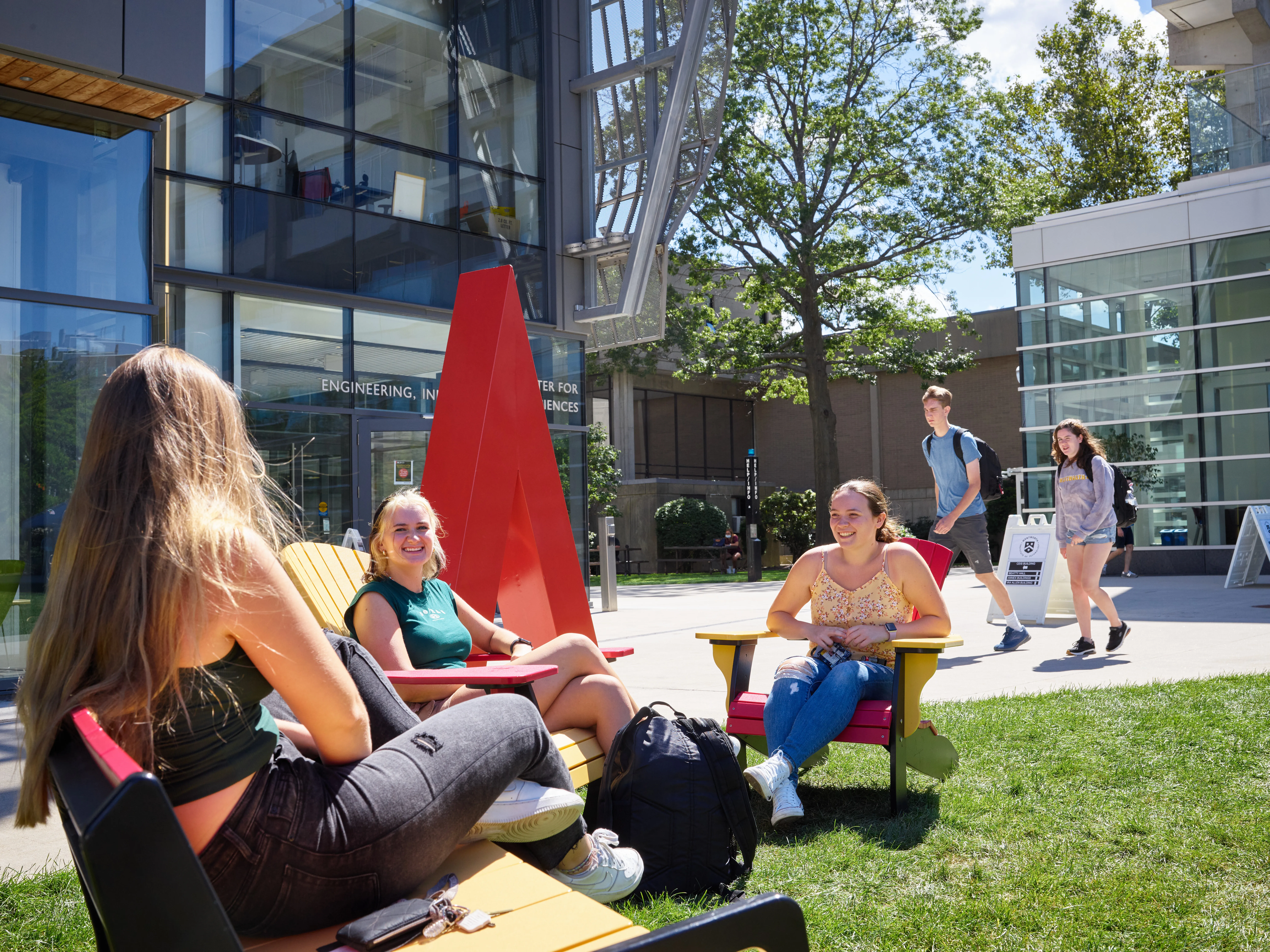 a group of students hanging out on a grassy quad
