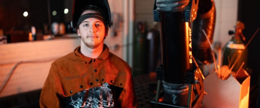 student posing in welders hat and gear