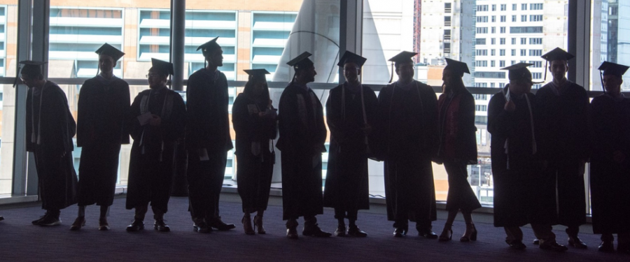 students graduates standing in front of a window