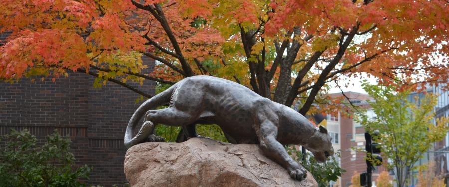 a leopard statue in front of orange leaves