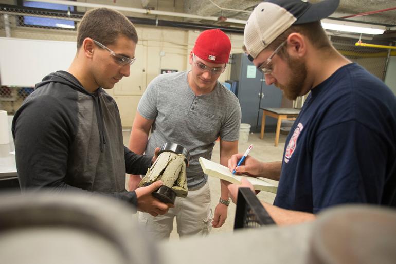 Three construction students testing cement mixture.