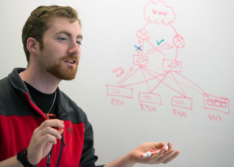 Male student explains diagram written on whiteboard.