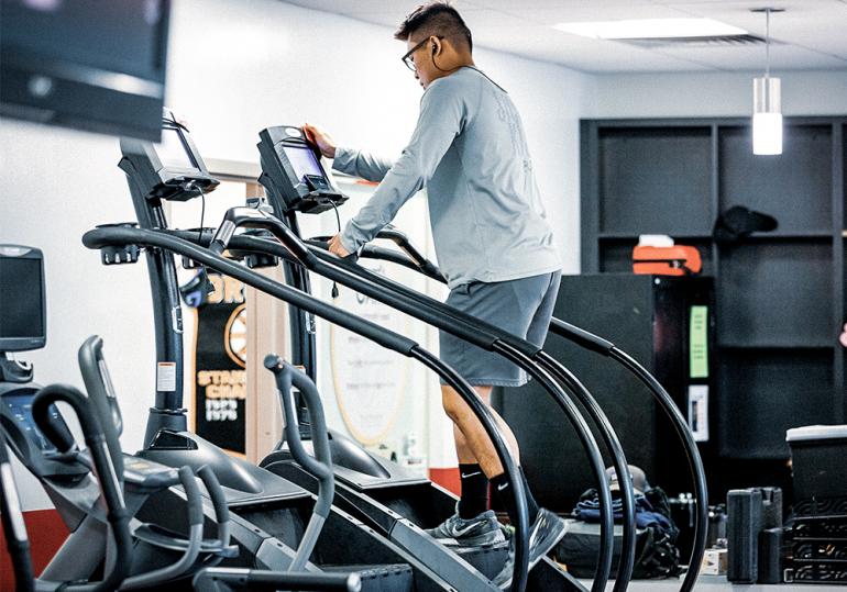 A man uses an elliptical machine in the Beatty Hall gym