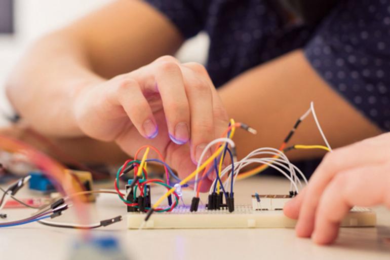 A closeup of a hand working on a project connection electrical wires.