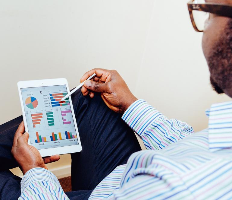 Man reviewing business graphs on tablet.
