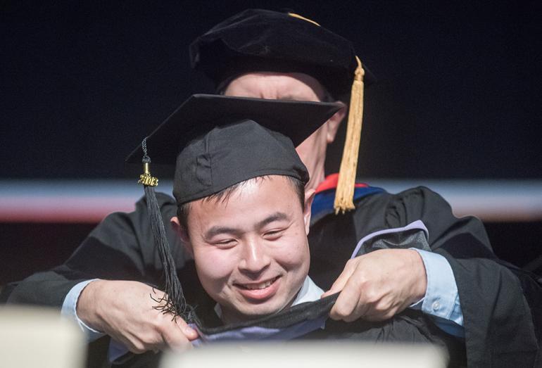 Graduate being hooded at commencement ceremony.