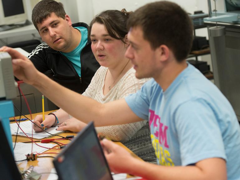 Students and instructor work on electrical engineering testing equipment. 