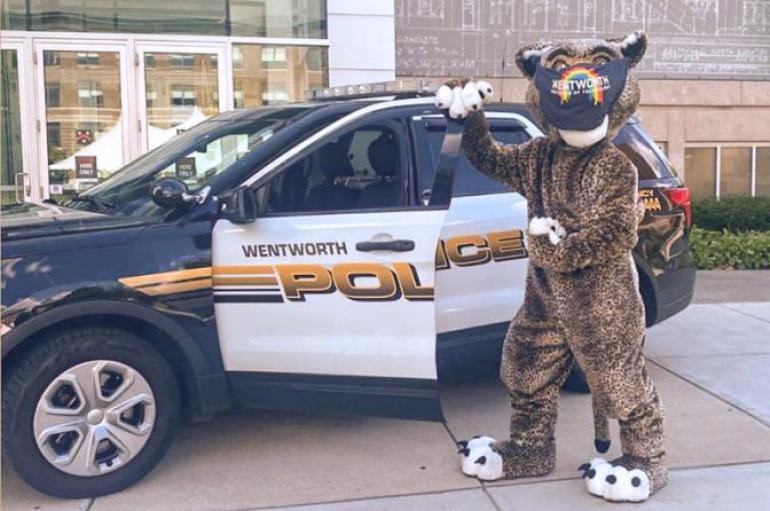 Leopard mascot wearing a mask in front of a Wentworth police car.
