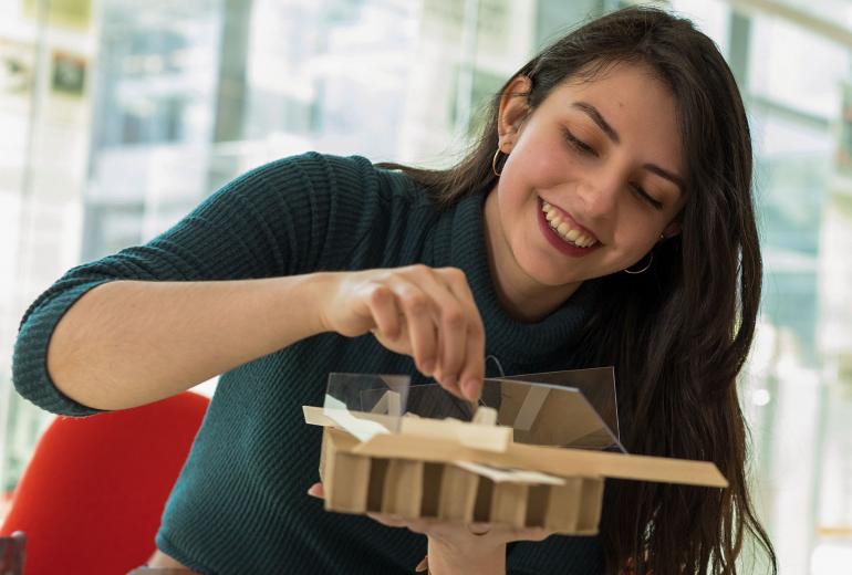 A woman smiles as she examines her architectural model.