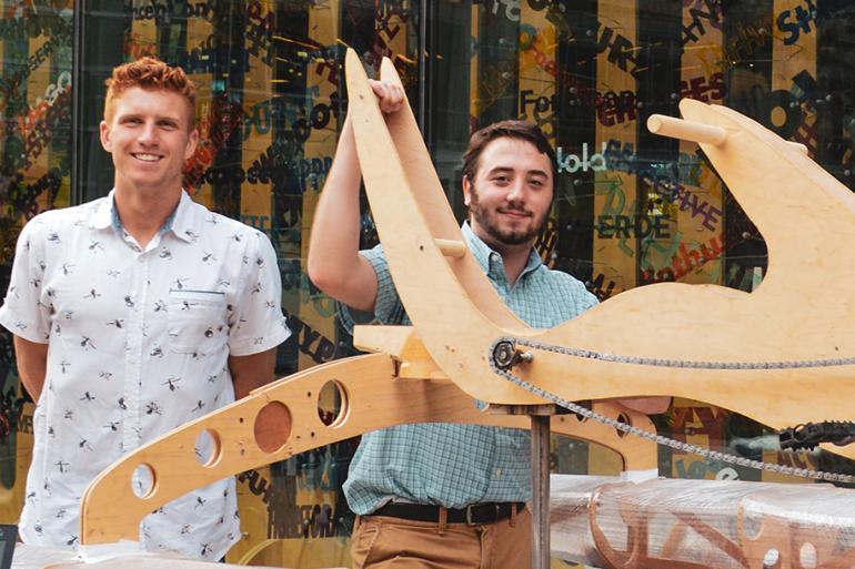 Two students stand with their plywood project. 