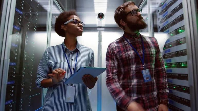 A female and male student monitor a server room for threats with a tablet computer