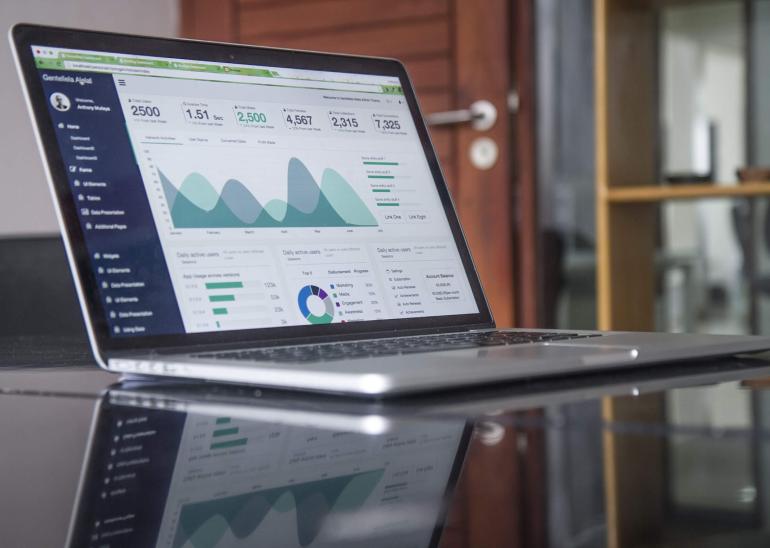 Stock photo of a laptop showing various pieces of data, numbers, charts, and graphs